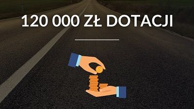 Kwota dofinansowania z dłonią przekazującą monety. W tle droga asfaltowa.
