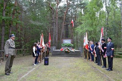Zdjęcie przedstawia poczty sztandarowe stojące przed pomnikiem poległych w Bitwie pod Huciskiem.