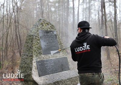 Wolontariusz fundacji czyszczący pomnik.